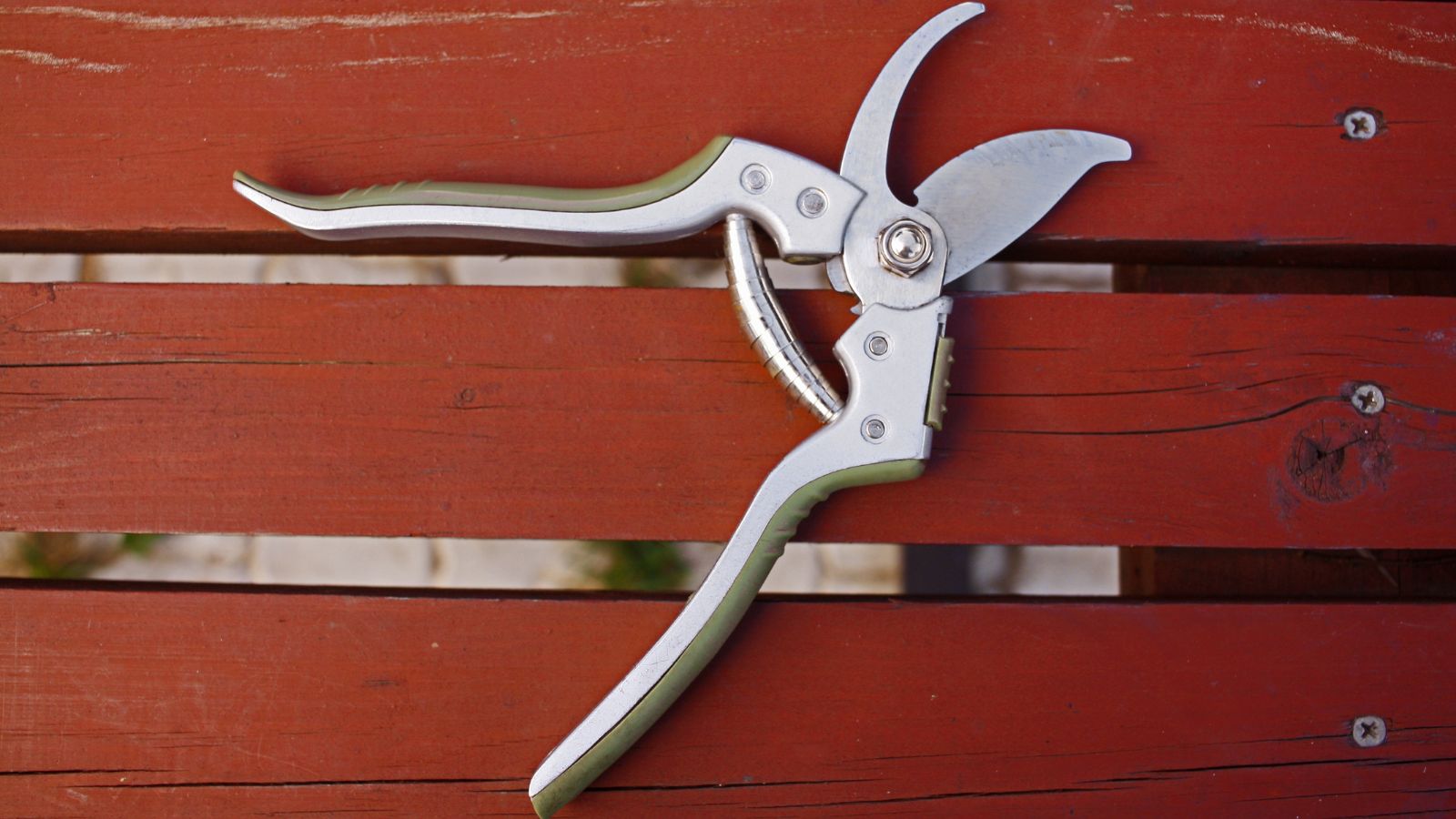 A close-up shot of silver gardening shears with rubberized handles on top of a wooden surface