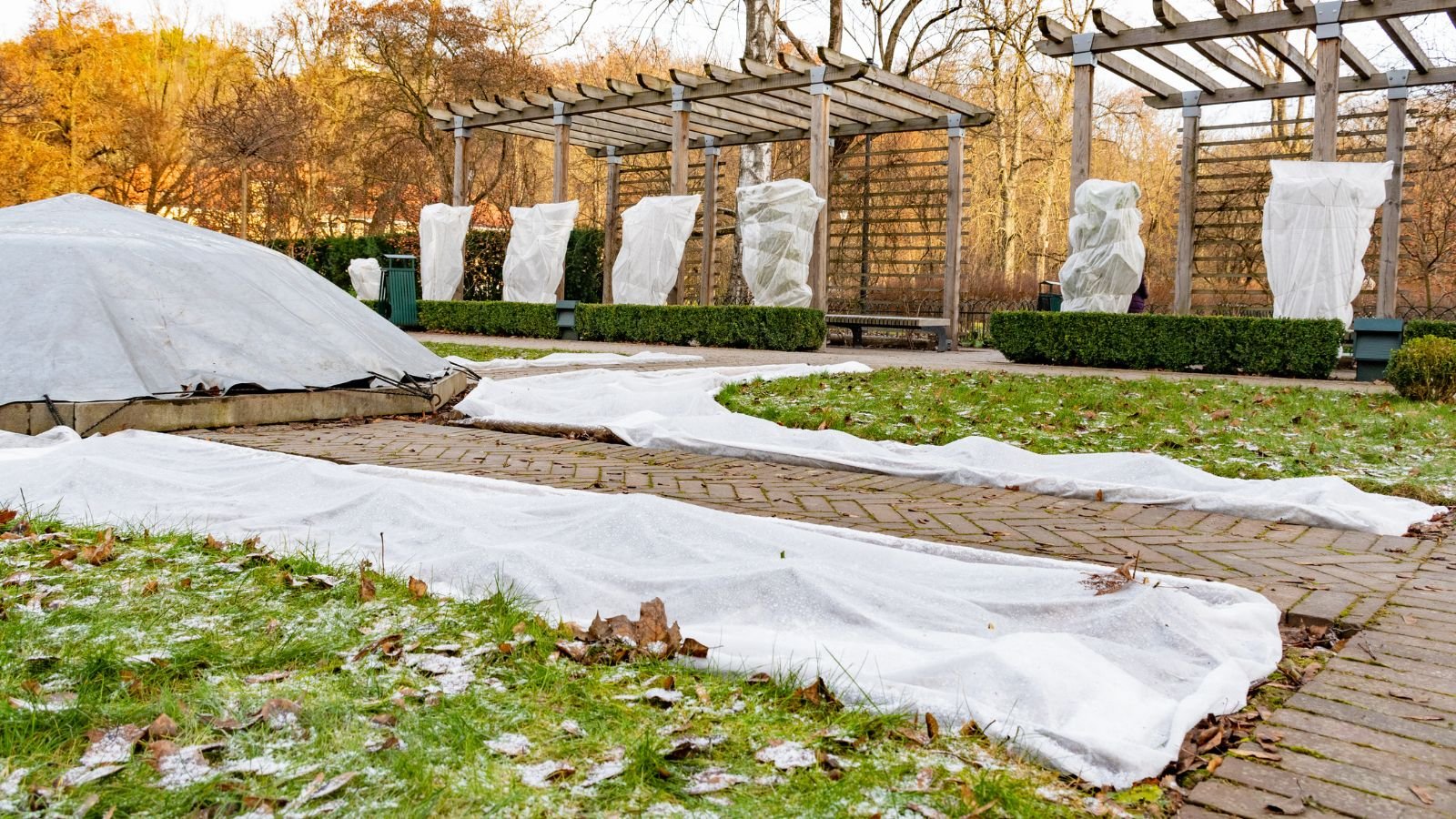 A shot of a garden with several layers of frost on top of a flower bed and multiple plants and flowers to protect them from temperature fluctuations.